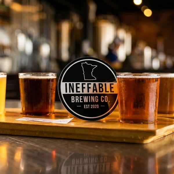 A wooden flight of five beers from Ineffable Brewing Co. on a reflective bar top.